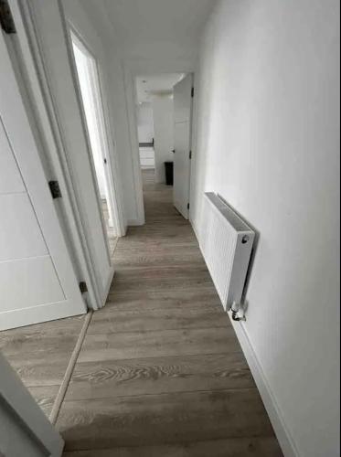 芬奇利2 Bedroom Luxury Appartment的空的走廊设有白色的墙壁和木地板