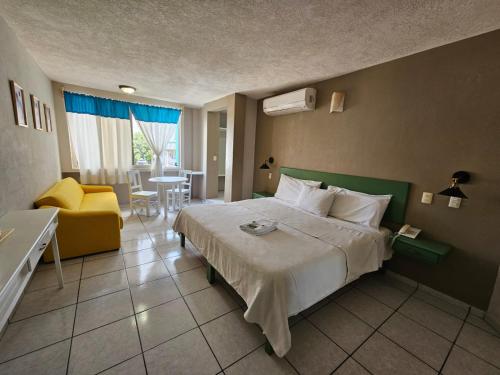 伊达尔戈州波萨里卡Hotel Punto Poza Rica的酒店客房,配有床和黄色椅子