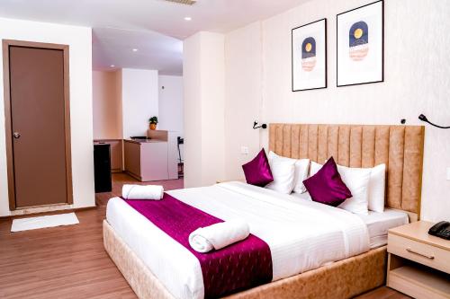 海得拉巴Casa Hotel & Suites, Gachibowli, Hyderabad的一间卧室配有一张带紫色枕头的大床