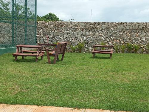 蓬塔卡纳Pool Breeze 202的两把长椅坐在草地上,靠近石墙