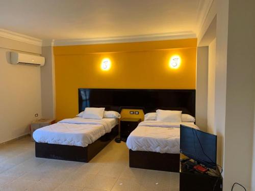 马萨阿拉姆Red sea Hotel Marsa Alam的一间酒店客房,设有两张床和电视