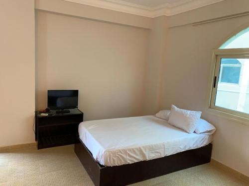 马萨阿拉姆Red sea Hotel Marsa Alam的一间卧室设有一张床、一台电视和一个窗口。