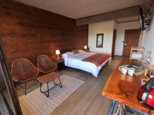 皮奇勒姆Esfera Pichilemu - Lodge的卧室配有一张床和一张桌子及椅子