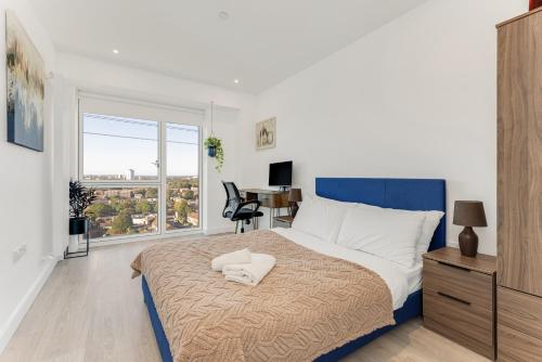 伦敦Docklands Two Bed Apartment的一间卧室配有一张床、一张书桌和一个窗户。