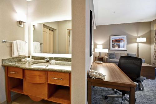 博伊西博伊西希尔顿惠庭套房酒店的一间带水槽的浴室和一张带椅子的桌子
