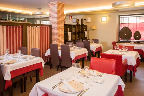 CretasHotel Villa de Cretas的一间设有白色桌子和红色椅子的餐厅