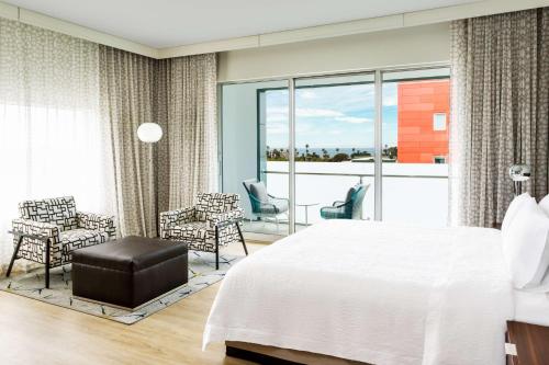 洛杉矶圣莫尼卡汉普顿酒店及套房的一间卧室配有一张床铺和椅子,设有一个阳台