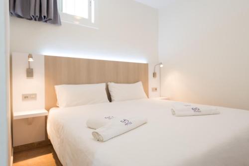 英格兰海滩EO拉斯罗萨斯公寓 的一张白色的床,上面有两条白色毛巾