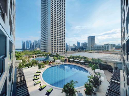 新加坡Swissotel The Stamford Singapore的享有带高楼游泳池的顶部景致