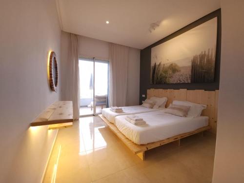 西迪拉哈尔Sidi Rahal Blue View, Piscine & mer sans vis-à-vis的卧室配有一张大床,墙上挂着一幅大画