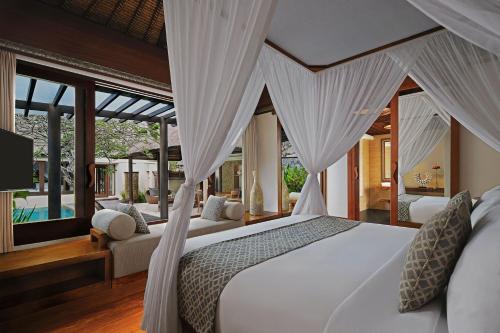 努沙杜瓦Amarterra Villas Resort Bali Nusa Dua, Autograph Collection的卧室配有带窗帘的白色床