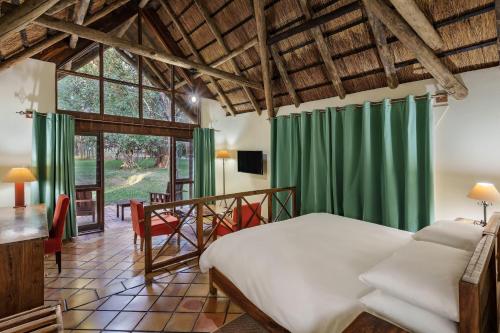 Chisamba普罗蒂亚野生酒店的一间卧室配有床、绿色窗帘和桌子