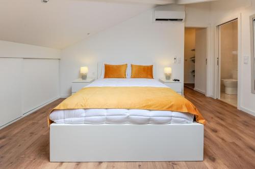 蒙蒂茹Boutique Room Montijo的白色卧室配有带橙色枕头的大床