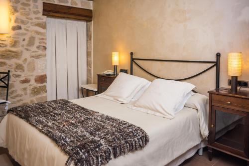 CretasHotel Villa de Cretas的一间卧室配有一张床和一张带两盏灯的桌子。