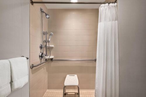米德尔顿西麦迪逊/米德尔顿万怡酒店的浴室设有淋浴帘和凳子。