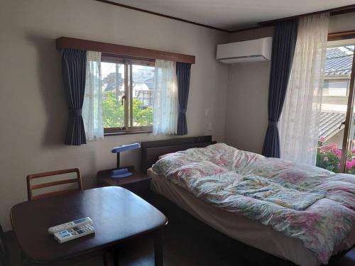 东京眺めのいい一軒家的卧室配有床、桌子和窗户。