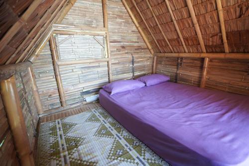 热浪岛Redang Campstay Bamboo House的小木屋内的卧室配有紫色床