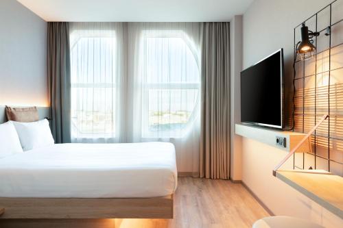 海牙Moxy The Hague的一间卧室配有一张床和一台平面电视