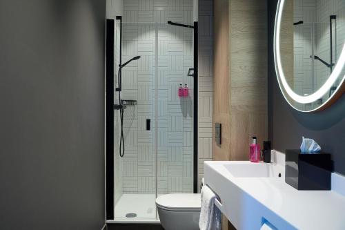 海牙Moxy The Hague的带淋浴、卫生间和盥洗盆的浴室