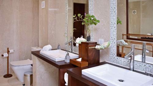 尼甘布Wattura Resort & Spa的浴室设有2个水槽、卫生间和镜子。