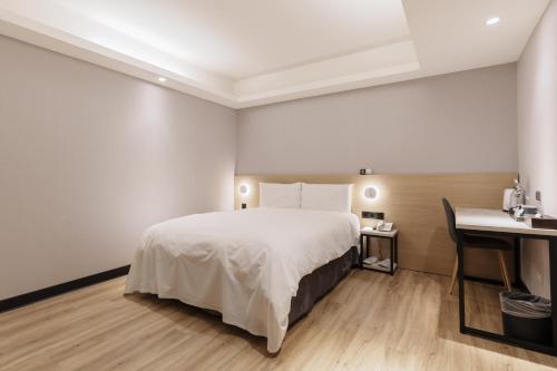 台北Hubhotel Benqiao Inn Far Eastern Branch的配有一张床和一张书桌的酒店客房