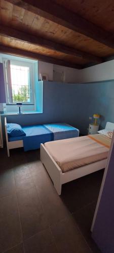 莱万托La Jeannotte的一间蓝色卧室,配有两张床和窗户