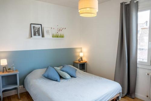 坎佩尔Les Hirondelles By Nid'Ouest的卧室配有一张带蓝色枕头的床,卧室设有窗户