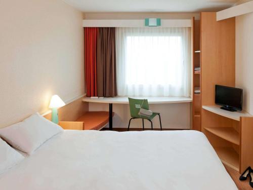 慕尼黑慕尼黑城北宜必思酒店的配有一张床、一张书桌和一扇窗户的酒店客房