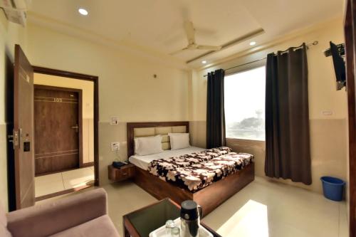 贾姆穆Royal Inn的一间卧室配有一张床、一张沙发和一个窗口