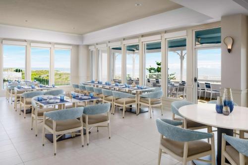 大洋城Hilton Garden Inn Ocean City Oceanfront的用餐室设有桌椅和窗户。