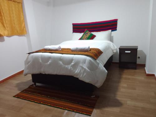 库斯科Incas Town Inn的一间卧室配有一张带白色毯子和枕头的床。