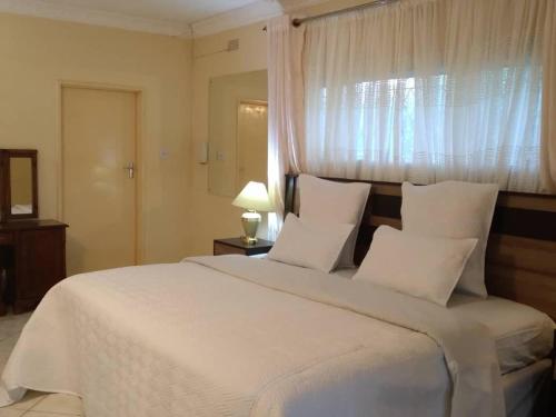 哈拉雷Charming 6-Bed House with Swimming Pool in Harare的卧室配有一张大白色床和窗户