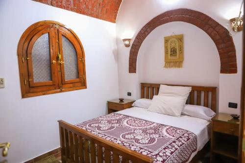 卢克索Shahhat House的一间卧室设有一张床和一个拱形窗户