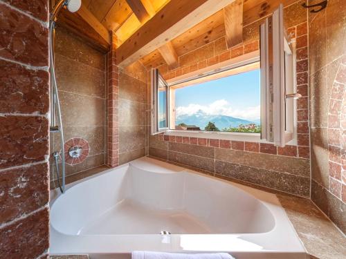 威拉尔-苏-罗伦阿尔卑斯如花酒店的带窗户的浴室设有大浴缸
