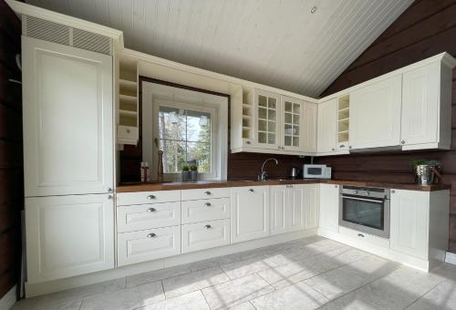 萨伦Mysig timmerstuga med utsikt över Tandådalens anläggningar的白色的厨房配有白色橱柜和窗户