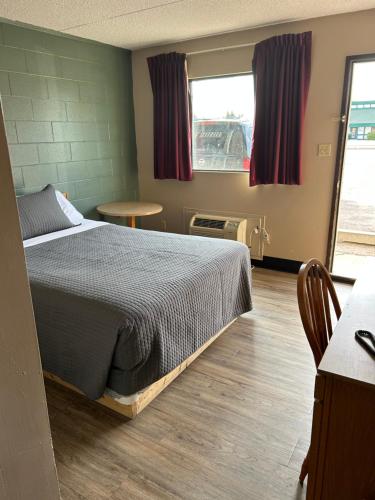 劳埃德明斯特瑟达汽车旅馆的一间卧室配有一张床、一张桌子和一个窗户。