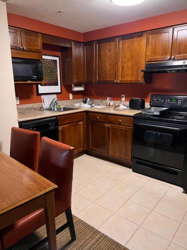 米西索加Queen bed available的厨房配有木制橱柜、桌子和炉灶。