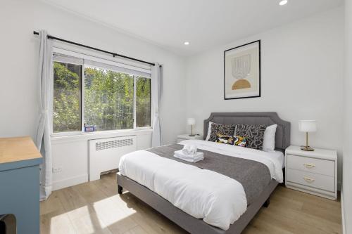 温哥华Spacious Fully Furnished 2-BR Suite的白色的卧室设有一张大床和一个窗户