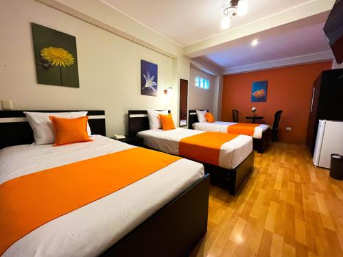 塔克纳Hotel PLATINIUM的酒店客房带两张带橙色床单的床