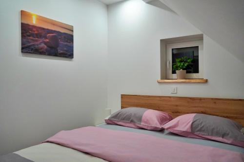 拉夫纳格拉Apartman Tilia的一间卧室配有带粉色和灰色枕头的床