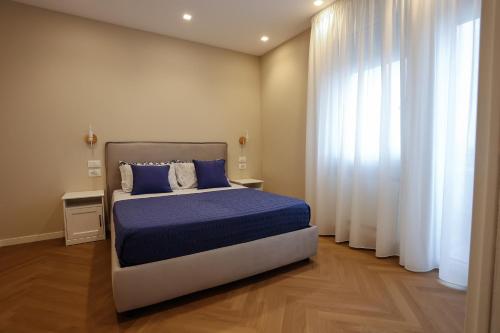 雷焦卡拉布里亚T&L-Home的一间卧室配有一张带蓝色床单和窗帘的床