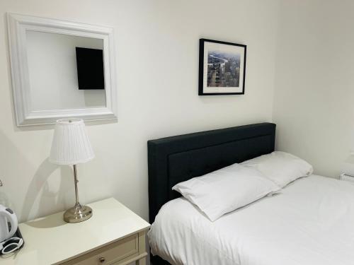 伦敦Riverside En suite Double Room E14的一间卧室配有一张床和一张带台灯的桌子