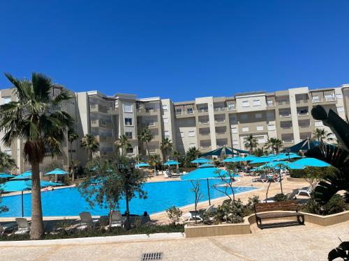 莫纳斯提尔Super appartement avec 5 piscines en résidence的一个带蓝色遮阳伞的大型游泳池的度假村