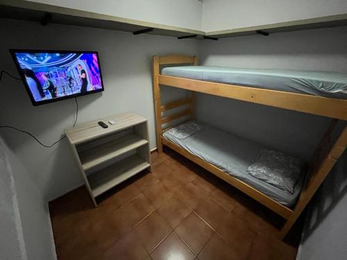 阿拉萨图巴Ritz Hostel的小房间设有两张双层床和电视