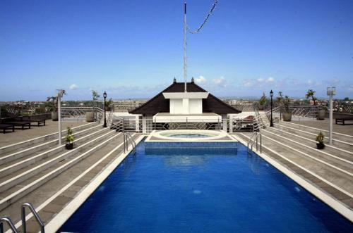 登巴萨巴厘岛天堂城市酒店的一座游泳池,其建筑背景为: