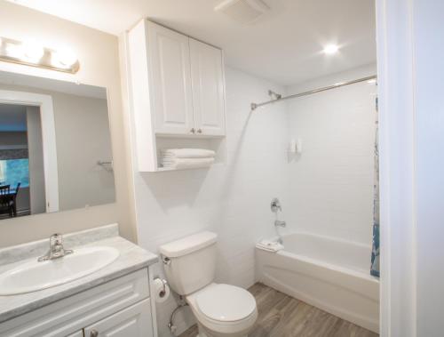 坎卢普斯Scott's Inn & Suites的白色的浴室设有卫生间、水槽和浴缸。