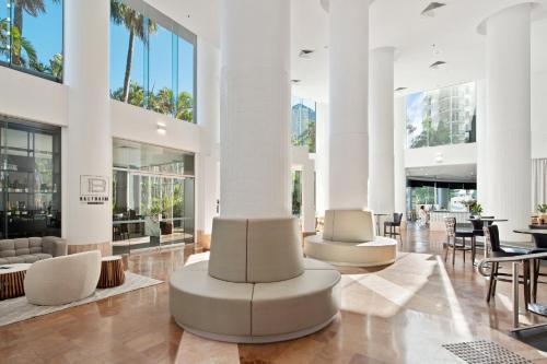 黄金海岸冲浪者天堂皇冠假日酒店的大堂设有白色的桌椅和棕榈树