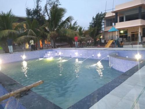 曼达莫尼Arya Beach resort的度假村内带灯光的大型游泳池