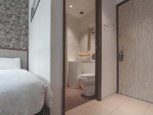 新加坡Noble Hotel的一间卧室配有一张床,浴室设有卫生间