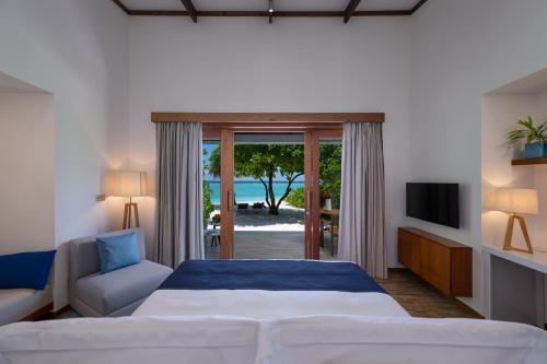 鲁阿环礁Ifuru Island Resort Maldives - 24-Hours Premium All-inclusive with Free Domestic Transfer的一间卧室设有一张床和一个滑动玻璃门